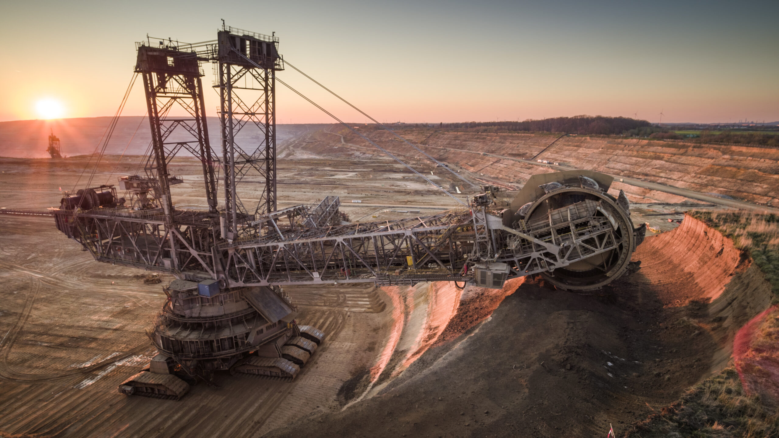Aerial shot of a large bucket wheel excavator excavating soil in an open pit lignite mine in Germany at sunset.
